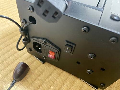 電源コネクタと、電源スイッチ（赤）。
黒いスイッチはスクリーンの上下スイッチ。
写真左下にあるケーブルから伸びている部分は、リモコンの赤外線受信センサーか？